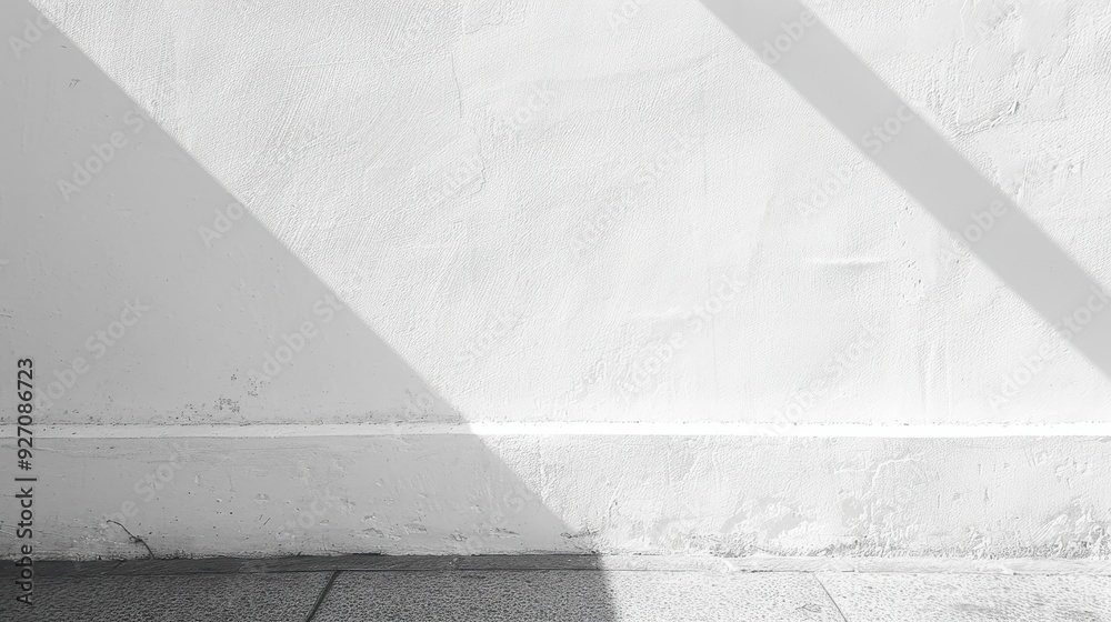 Poster a white wall with a diagonal shadow cast on it. the wall has a white trim at the base, below which i