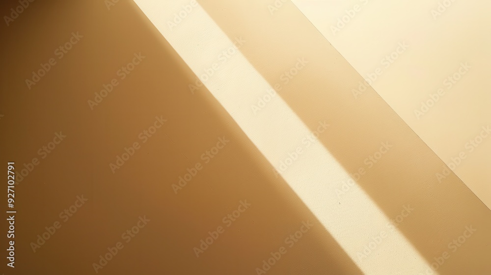 Poster Sunlight streams through a window, casting a diagonal beam of light across a beige wall. The light creates a contrast with the darker wall, highlighting the texture of the surface.