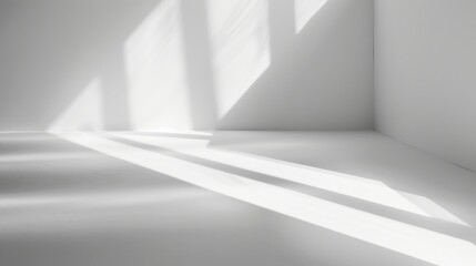 Sunlight streams through a window and casts long, rectangular shadows across the white floor of an empty room. The walls are also white, creating a minimalist and clean aesthetic.