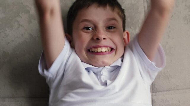 concept of joy of boy using phone, caucasian boy 10 years old looking at smartphone screen and surprisedly happy sitting on sofa at home