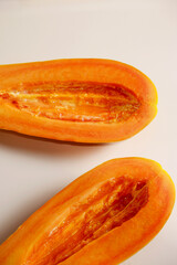 Half-papaya without seeds on a beige-orange background. Close-up two ripe papayas for freshness, food texture, slice, cut fruit, eating healthy concepts. Beautiful papaya slice texture without seeds.