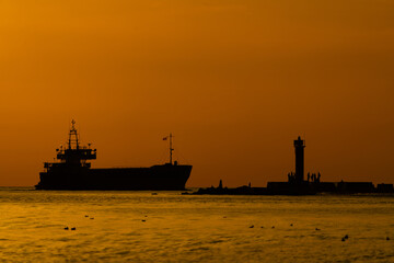 Obraz premium A large boat floats on the water's surface, beside a lighthouse towering above it