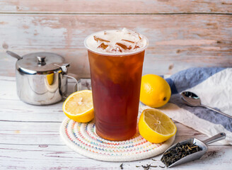 Iced lemon black tea with sugar pot and spoon served in disposable glass isolated on table side...