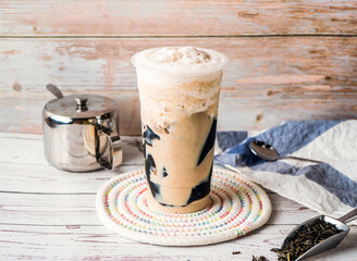 Iced Grass Jelly Milk Tea with sugar pot and spoon served in disposable glass isolated on table side view of hong kong tea