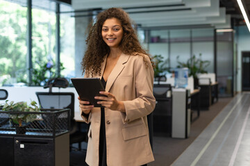 Businesswoman uses digital tablet standing in the office corridor