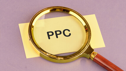 PPC. Pay Per Click concept Businessman working concept, social network, SEO. PPC written through a magnifying glass on yellow paper