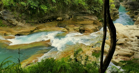 malerischer, Auslauf  des Wasserfalls Tanggedu auf der Insel Sumba in Indonesien zwischen Felsen und vor gr&uuml;nem Wald