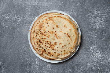 Pancakes on a plate, top view, isolated on gray textured background.