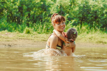Fototapeta premium mom and child swim in the river