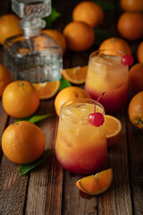 Tequila sunrise cocktail garnished with a maraschino cherry.