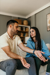 Couple sitting on the couch trying to solve the problems at home in the living room