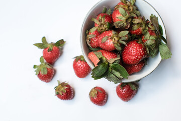 Heap of fresh strawberries in white ceramic bowl on rustic white background, fresh fruits.