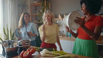 Cinematic image of a group of senior women cooking and having fun at home. Reunion and social gathering of three female friends in a beautiful kitchen.