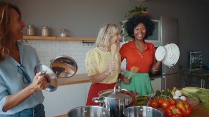 Cinematic image of a group of senior women cooking and having fun at home. Reunion and social gathering of three female friends in a beautiful kitchen.