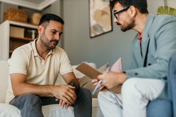 Young man having counseling with mental health professional in the bright living room