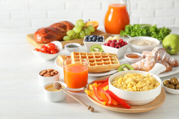 Tasty breakfast. Scrambled eggs in bowl, cut bell pepper, honey and other food on light table