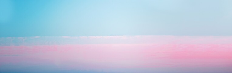 Fototapeta premium A hazy, pastel sky at sunset with soft pink and blue colors. The sky is almost entirely clear with only a few wispy clouds visible.