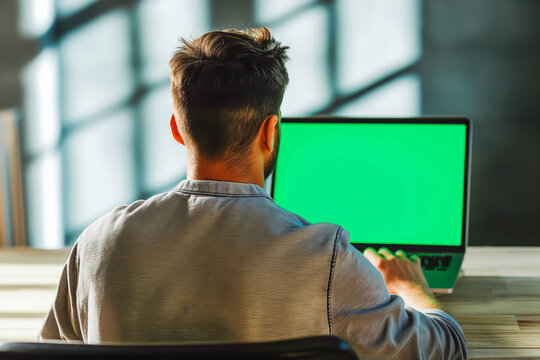 Rearview shot of an unrecognizable young man using his laptop with green screen