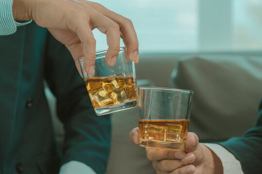 Businessmen discussing work and drinking Vikis in a dark room, close-up photo
