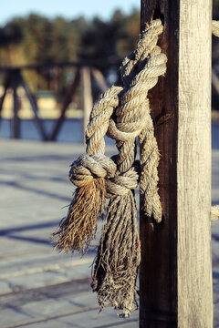 Closeup of the two-strand twisted natural fiber ropes with knots on their ends as a part of a retro-style enclosure