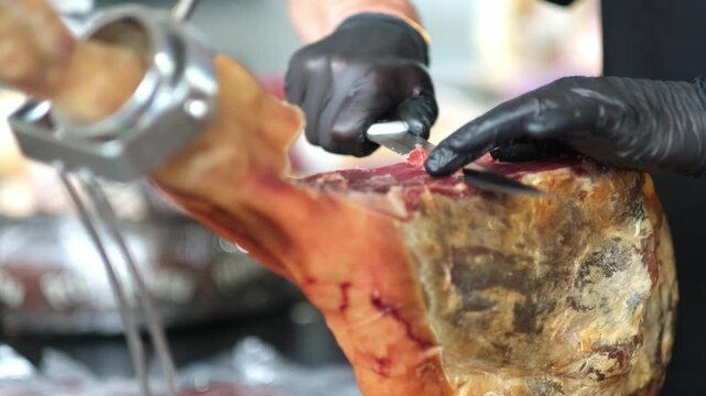 close up of hands man Chef cutting Extra quality dry-cured spanish ham Jamon very appetizing. detailed image of a ham cutter with knife cutting a thin slice of Iberico jamon. 4K.