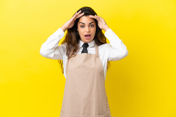 Young caucasian restaurant waiter isolated on yellow background with surprise expression