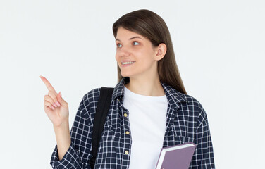 Hey look. Smiling pretty female model pointing fingers left at empty space and inviting to check it out, showing advertisement on white background. Girl with notepads in hands.