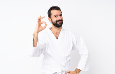 Naklejka premium Young man doing karate over isolated white background showing ok sign with fingers