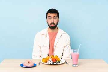 Man at a table having breakfast waffles and a milkshake with sad and depressed expression