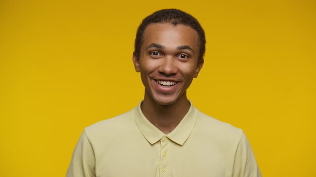 Smiling Young Man Nodding Head in Approval Against Yellow Background