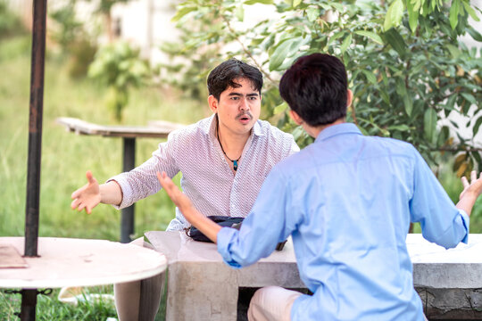 Two men arguing each other in the park. 2 men debate with each other, blame each other