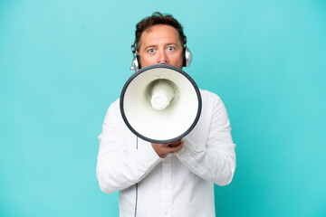 Telemarketer caucasian man working with a headset isolated on blue background shouting through a megaphone