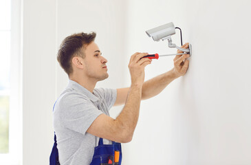 Cctv camera wall installation by professional male technician at wall with screwdriver. Repairing...