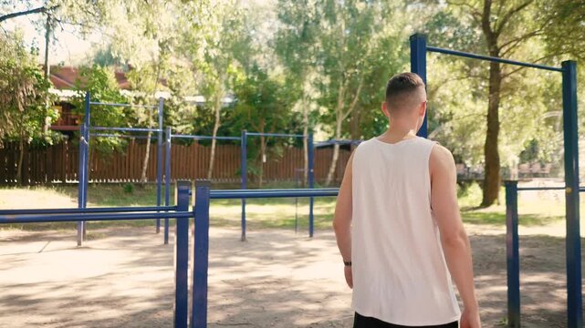 Handsome pumped up young male bodybuilder doing exercises on horizontal bar and parallel bars outdoors on the street. Beautiful male body shapes, beauty and health, training and motivation