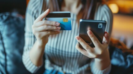 A person holding a smartphone in one hand and a credit card in the other, preparing for an online shopping transaction on a modern couch.