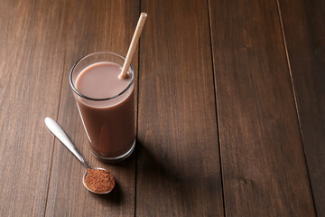 Delicious protein shake in glass and spoon with powder on wooden table, space for text