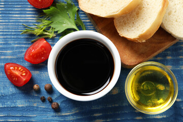 Balsamic vinegar, bread and other products on blue wooden table, flat lay
