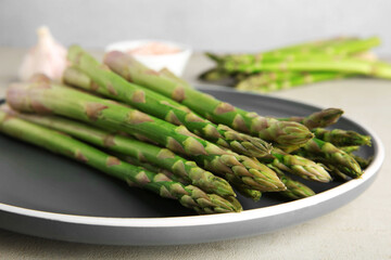 Fresh green asparagus stems on gray table, closeup