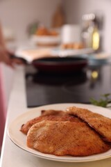 Plate of tasty schnitzels on table in kitchen, closeup