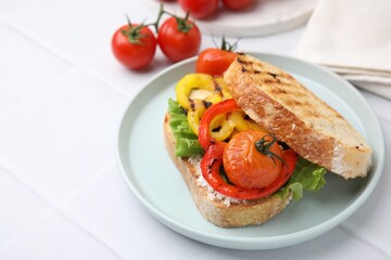 Tasty sandwich with grilled vegetables and cream cheese on white tiled table, closeup. Space for text