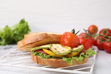 Tasty sandwich with grilled vegetables on white tiled table, closeup
