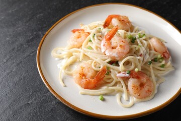 Delicious pasta with shrimps and green onion on black table, closeup