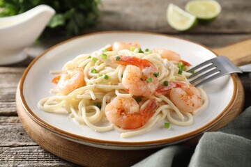 Delicious pasta with shrimps and green onions on wooden table, closeup