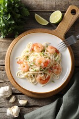 Delicious pasta with shrimps, green onions, lime, garlic and parsley on wooden table, flat lay