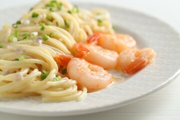 Delicious pasta with shrimps and green onions on white wooden table, closeup