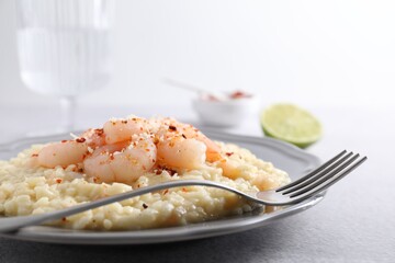Delicious risotto with shrimps and cheese on light grey table, closeup