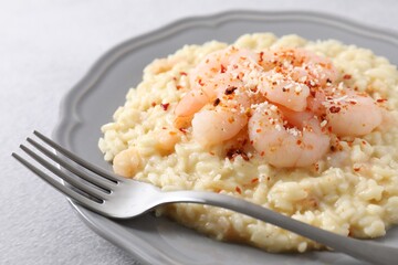 Delicious risotto with shrimps and cheese on light grey table, closeup