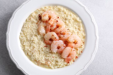 Delicious risotto with shrimps and cheese on light grey table, top view