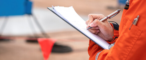 Action of safety officer is writing and check on checklist document during safety audit and...
