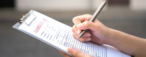 Foreman's hand is using a pen checking on building inspection report form to QC building quality of...